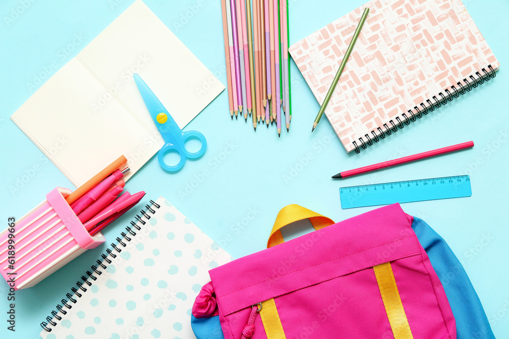 Frame made of school backpack and different stationery on blue background