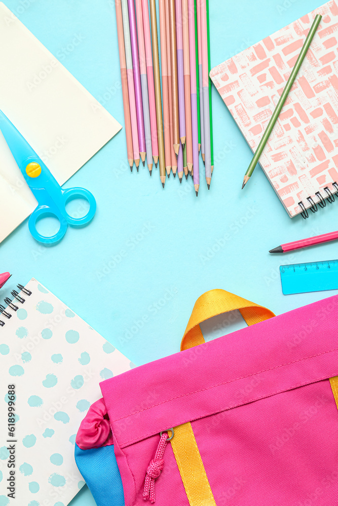 Frame made of school backpack and different stationery on blue background