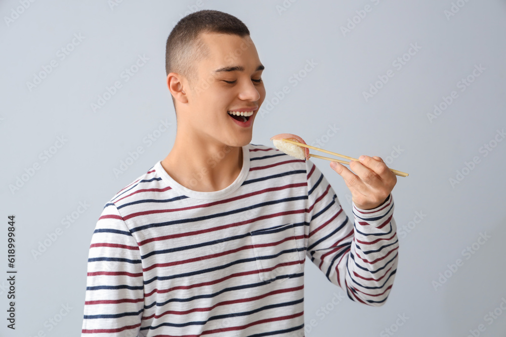 Young man with tasty sushi on light background