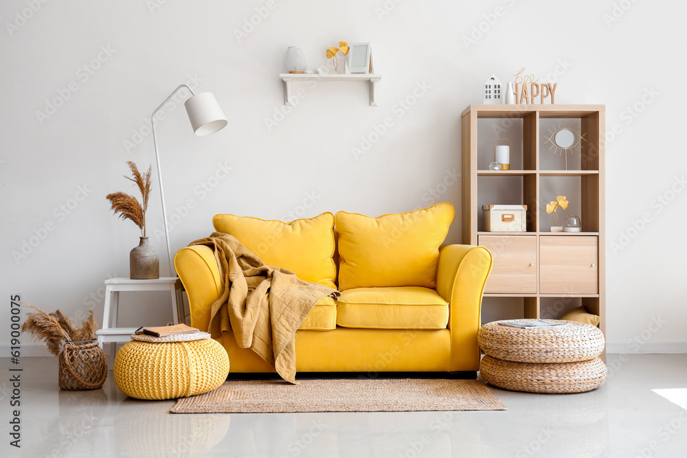 Interior of light living room with stylish yellow sofa and soft poufs