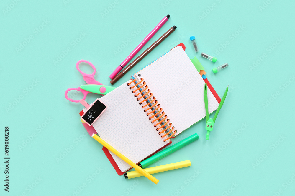 Blank notebook with different stationery on turquoise background