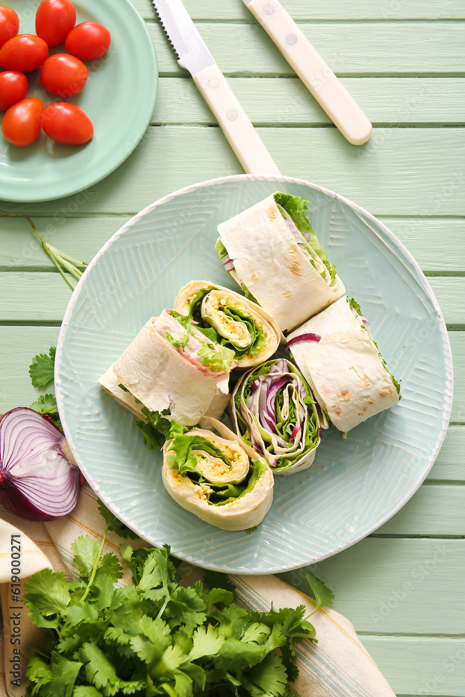 Plate of tasty lavash rolls with onion and egg on green wooden background