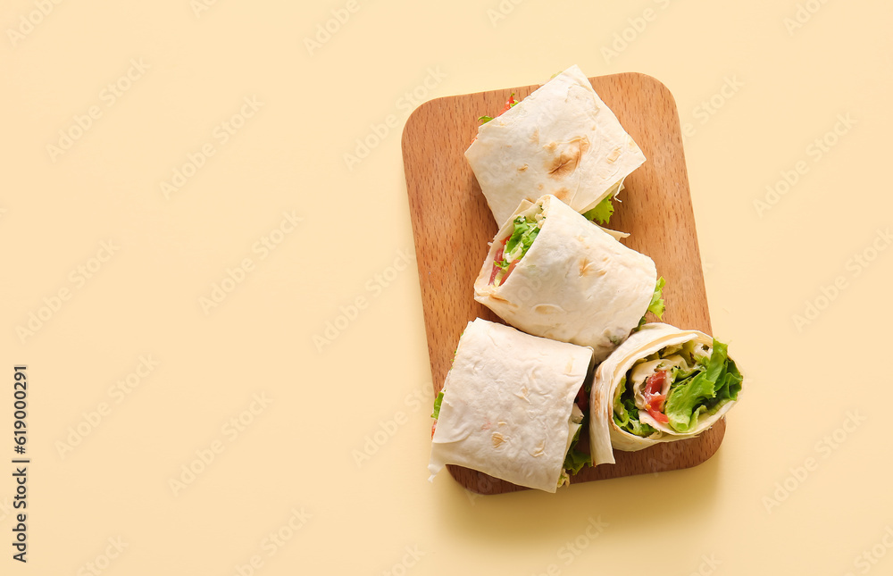 Wooden board of tasty lavash rolls with tomatoes and greens on beige background