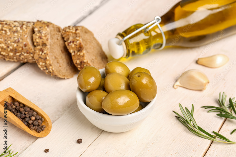 Bowl with ripe olives on light wooden background