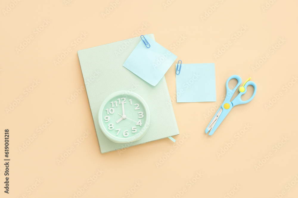 Alarm clock with different stationery on pale orange background