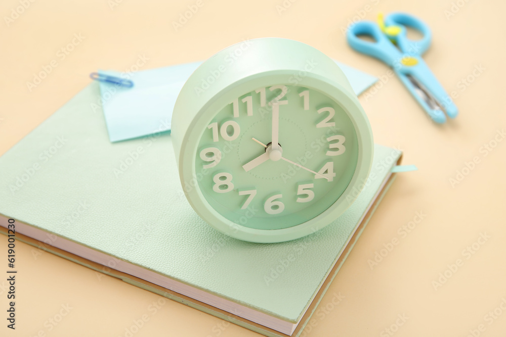 Alarm clock with different stationery on pale orange background