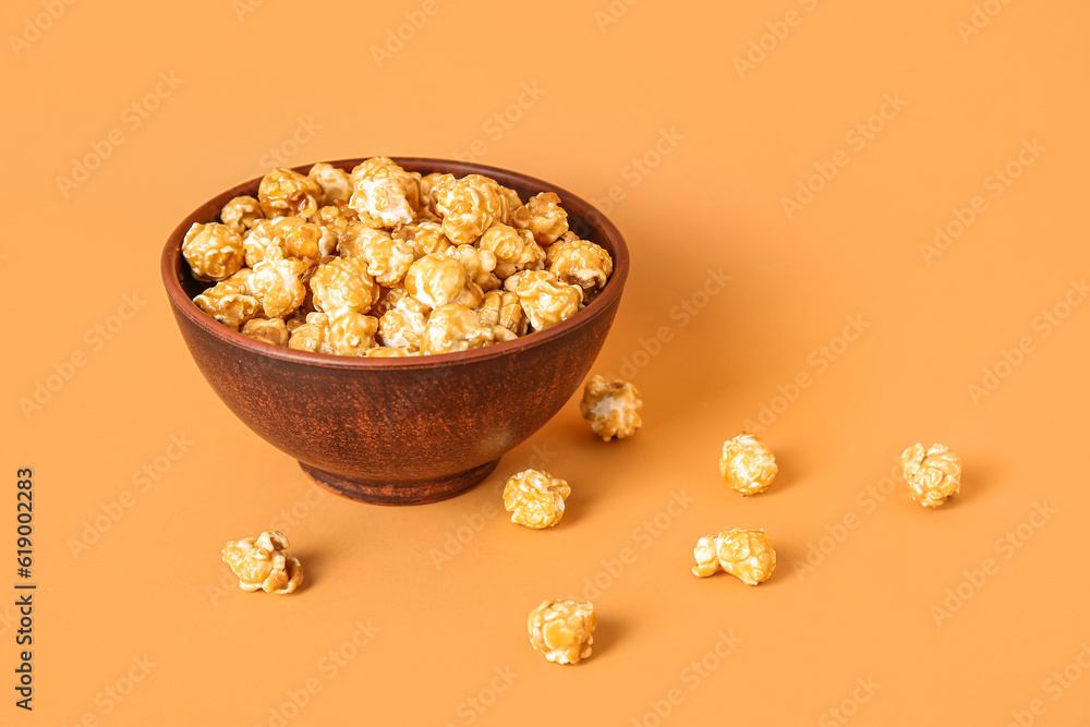 Bowl with tasty popcorn on brown background