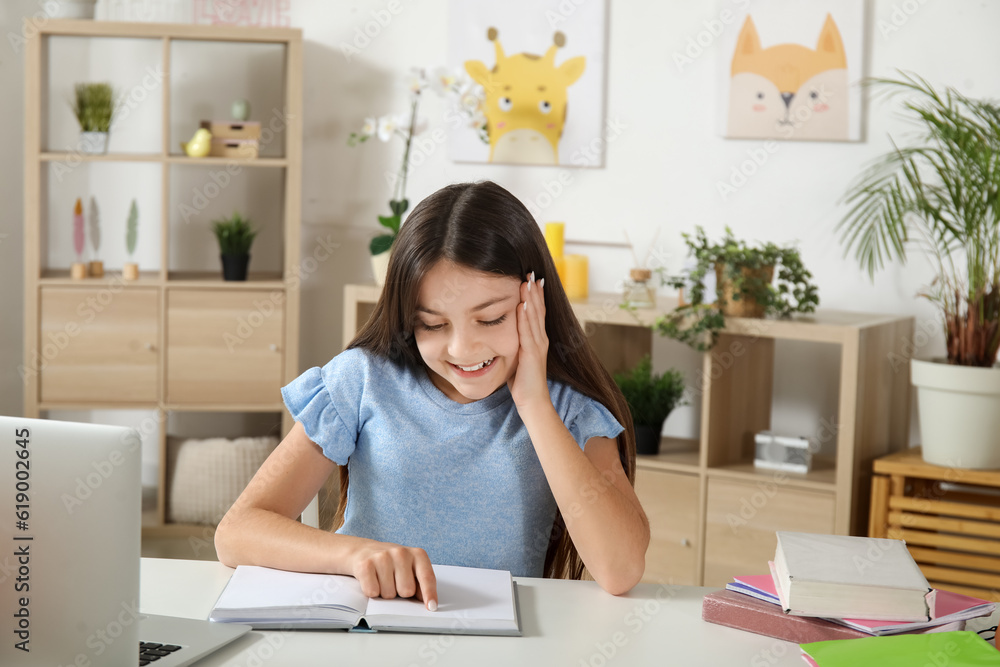 Little girl reading schoolbook at home