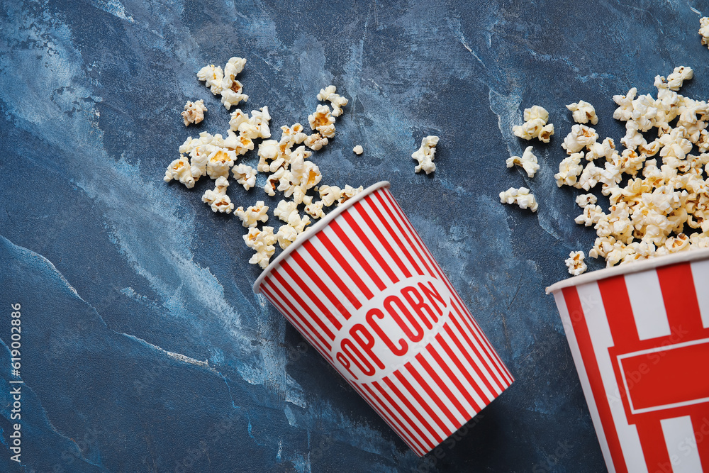 Buckets with tasty popcorn on blue background