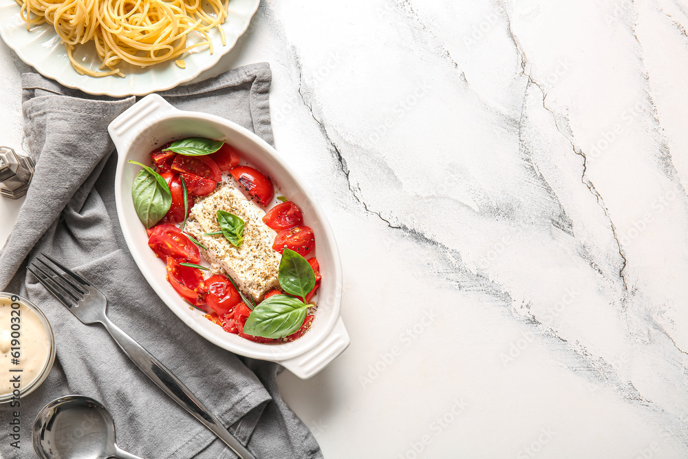 Baking dish with tasty tomatoes and feta cheese on white marble background