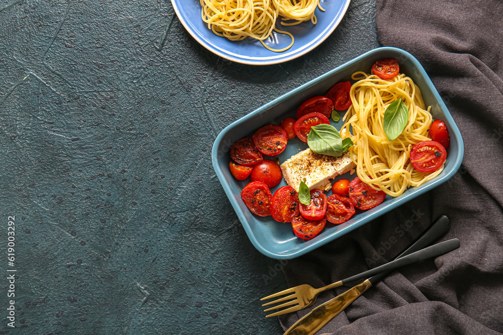 Baking dish of tasty pasta with tomatoes and feta cheese on blue background