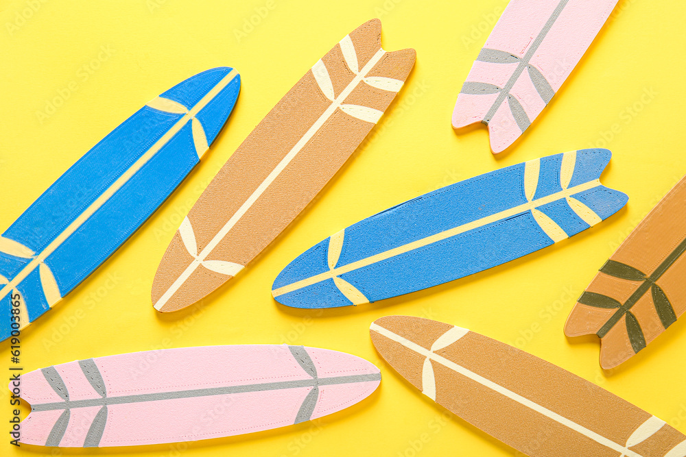 Many different colorful mini surfboards on yellow background