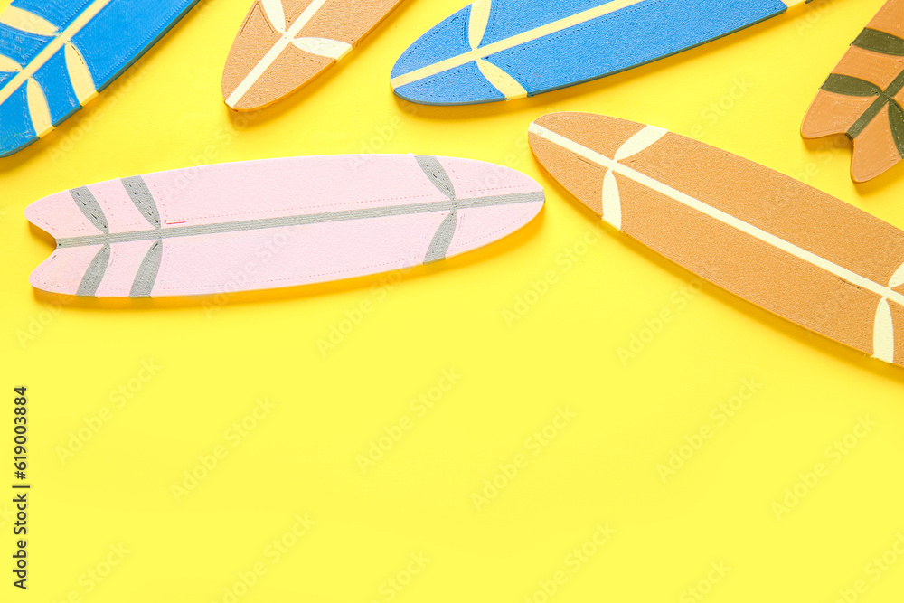 Many different colorful mini surfboards on yellow background