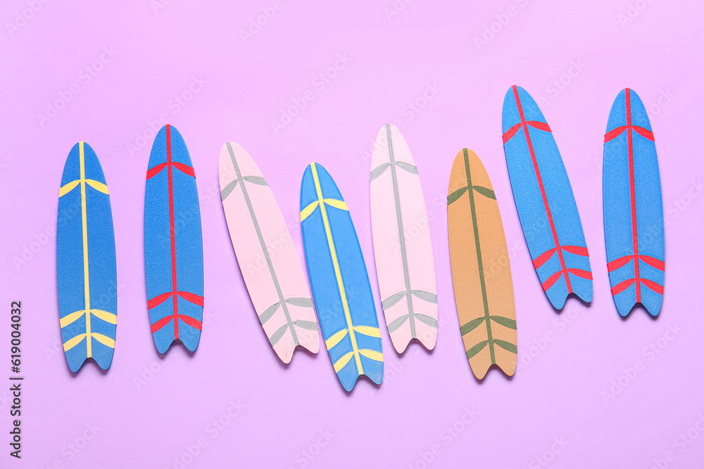 Many different colorful mini surfboards on lilac background