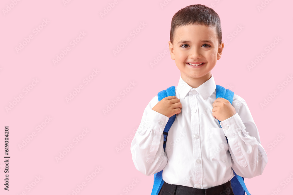 Little schoolboy with backpack on pink background