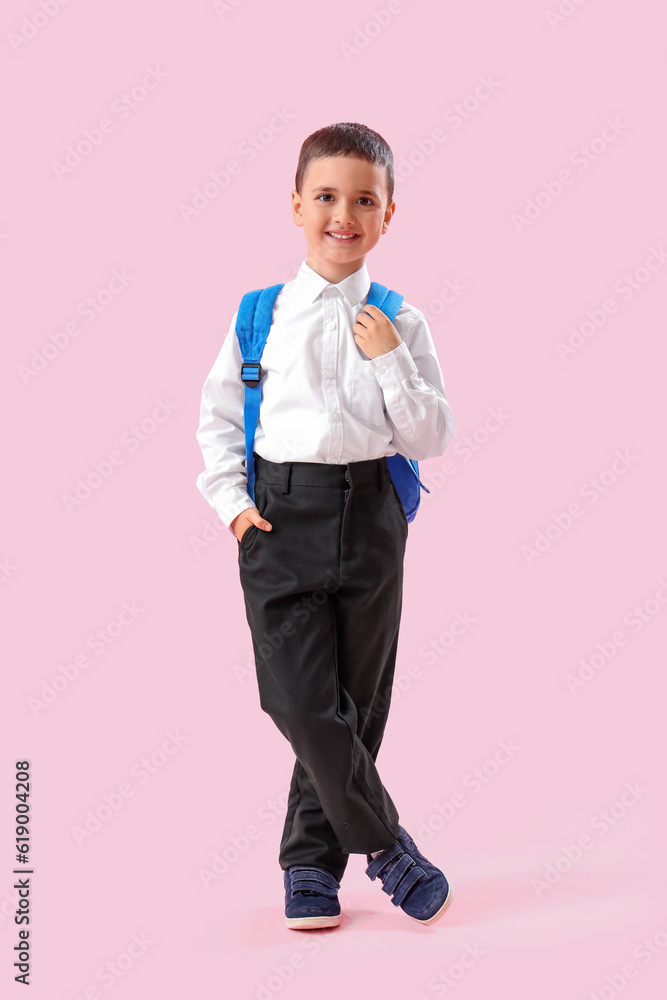 Little schoolboy with backpack on pink background