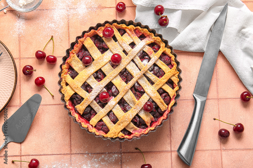 Baking dish with tasty cherry pie on pink tile background