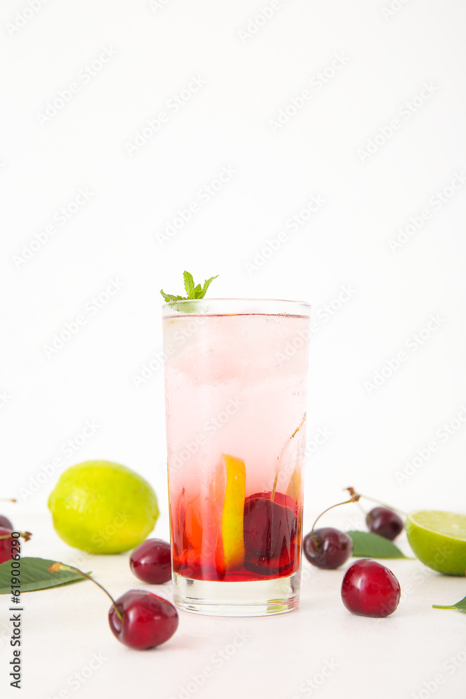 Glass of tasty cherry lemonade with lime and mint on white background