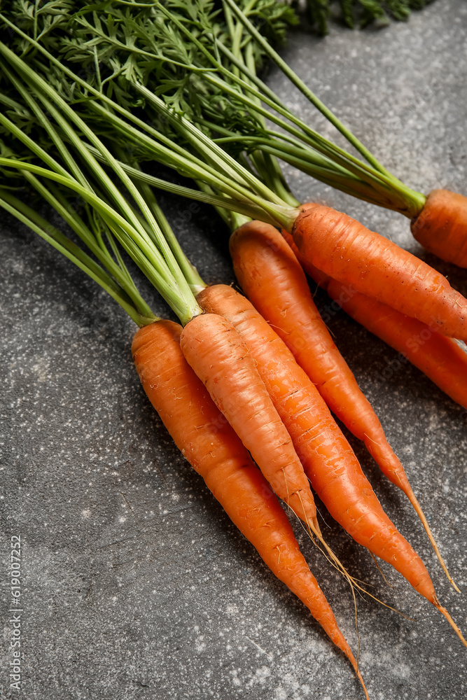 Fresh carrots with leaves on grey background