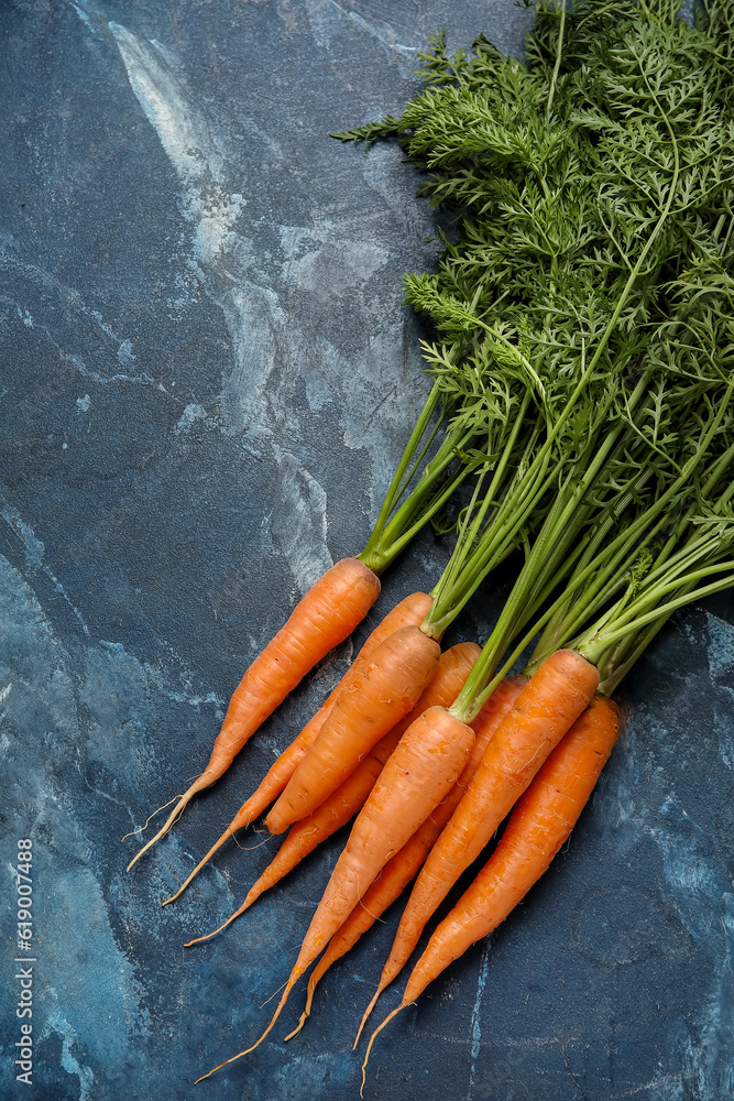 Fresh carrots with leaves on blue background