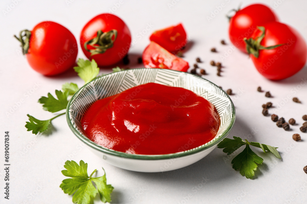 Bowl with tomato paste and fresh vegetables on grey background