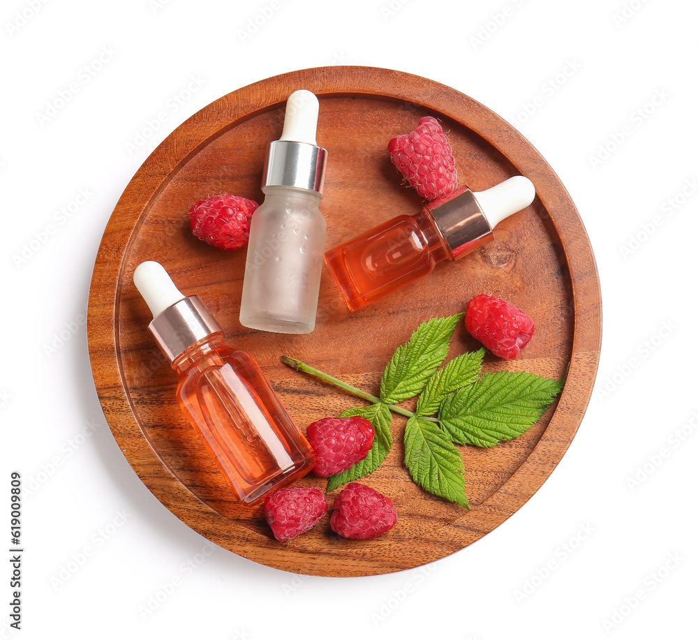 Wooden board with bottles of cosmetic raspberry oil on white background