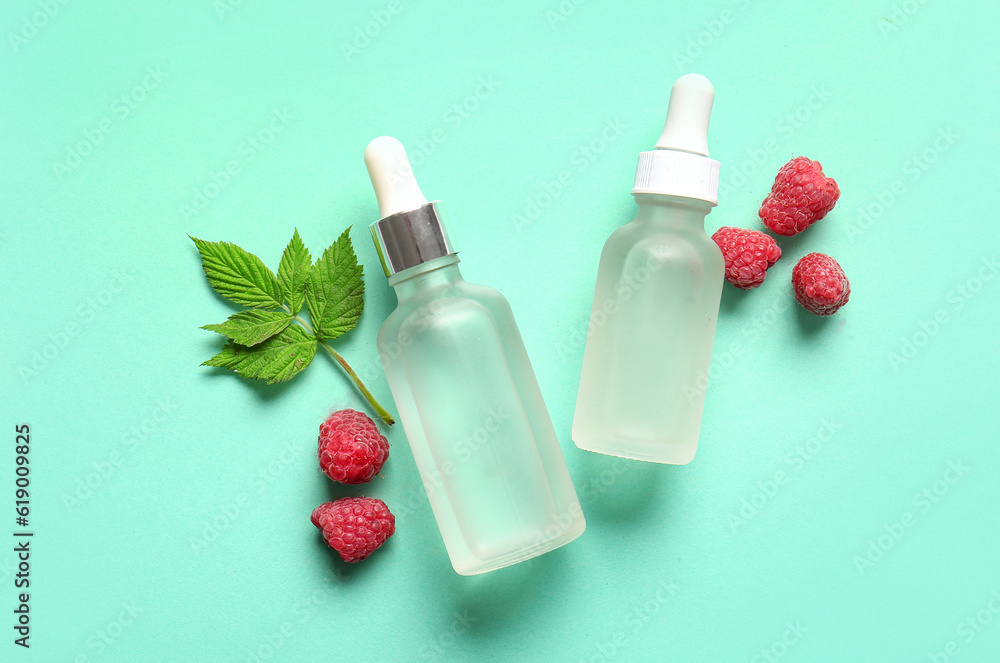 Bottles of cosmetic raspberry oil on blue background