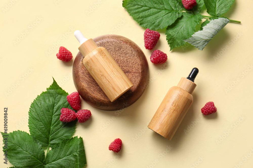 Bottles of cosmetic raspberry oil on yellow background