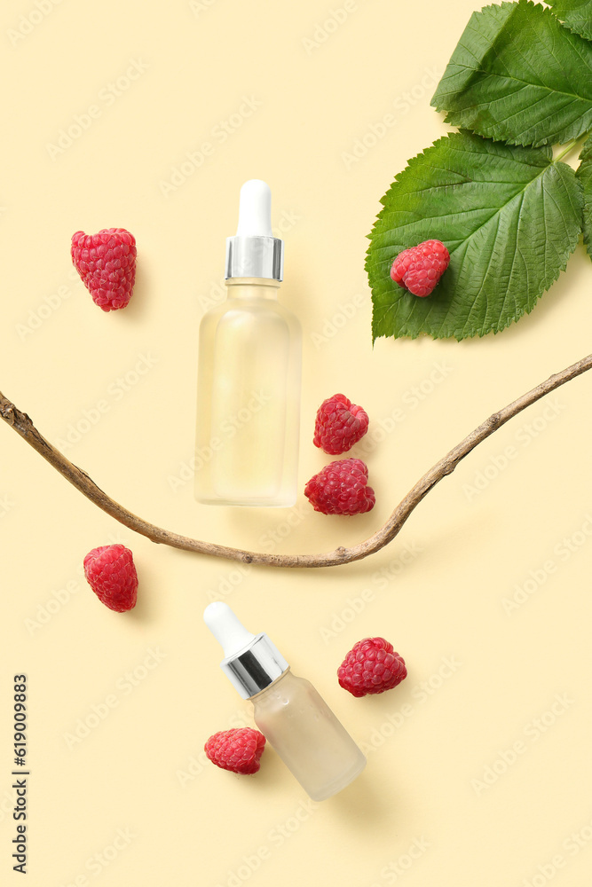 Bottles of cosmetic raspberry oil on yellow background