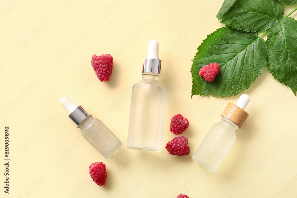 Bottles of cosmetic raspberry oil on yellow background