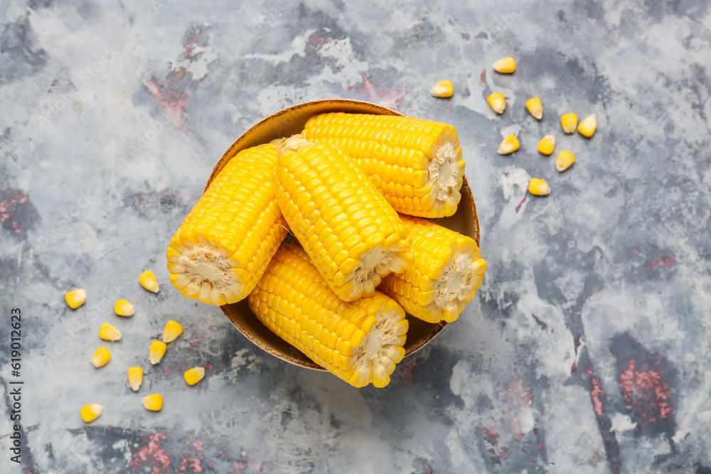 Bowl with cut fresh corn cobs and seeds on blue background