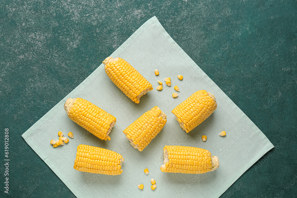 Cut fresh corn cobs and seeds on green background