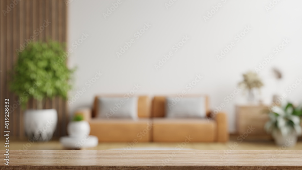 Wood table top on blur living room have leather sofa and decoration minimal.