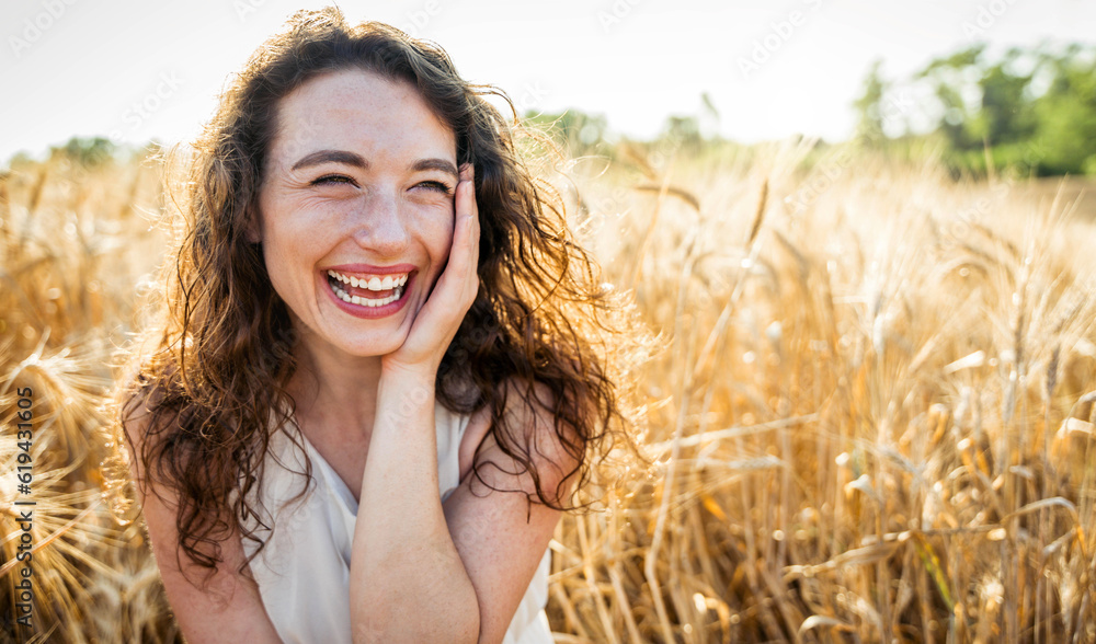 Happy beautiful woman smiling in a wheat field - Delightful female enjoying summertime sunny day out