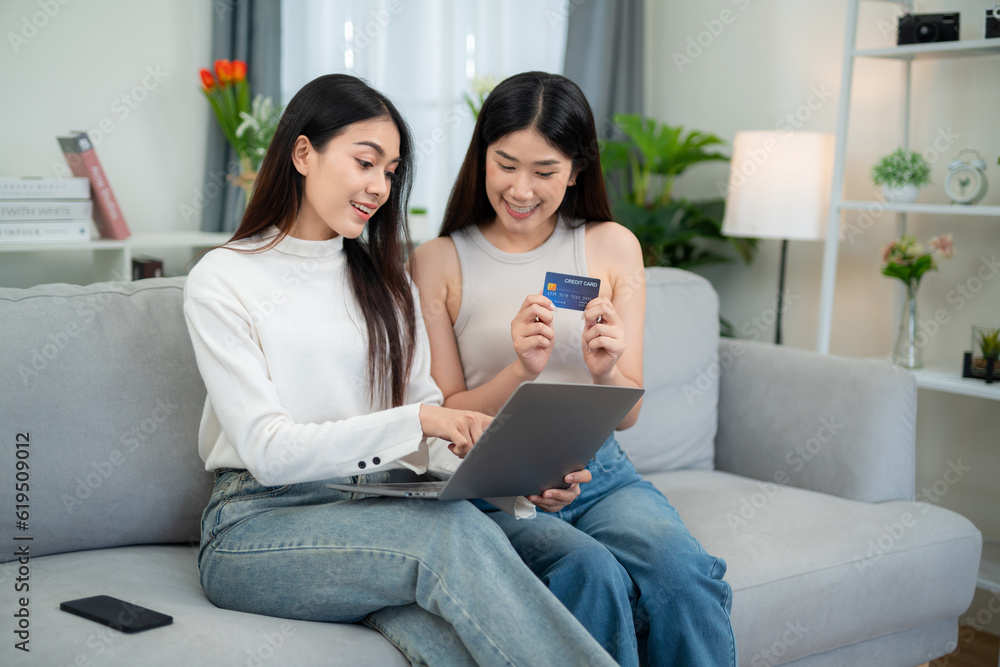 Two beautiful young women are using credit cards to make purchases. online shopping in living room. 