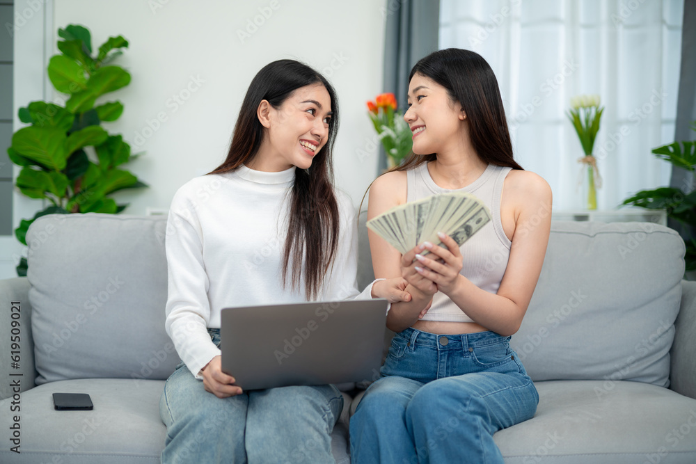 Two young asian women enjoying online business financial planning in living room. Finance and e-comm