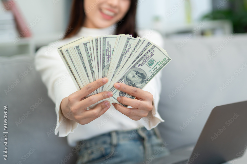 Close up hand of Woman showing cash with laptop on sofa in living room. online business and e-commer