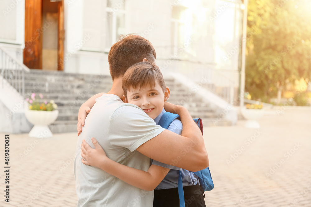 Father hugging his little son near school