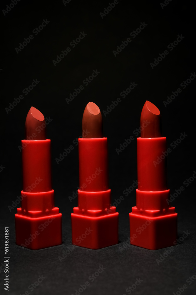 Set of beautiful red lipsticks on dark background