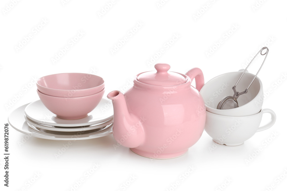 Ceramic teapot with cups, tea infuser and saucers on white background