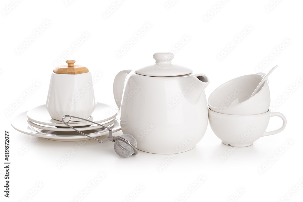 Ceramic teapot with cups, sugar bowl, tea infuser and saucers on white background