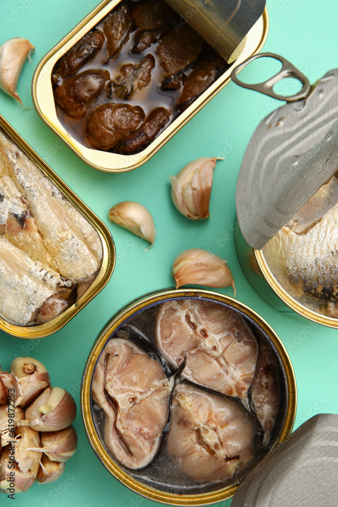 Opened tin cans with different fish and mussels on turquoise background