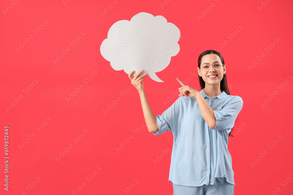 Young woman pointing at blank speech bubble on red background