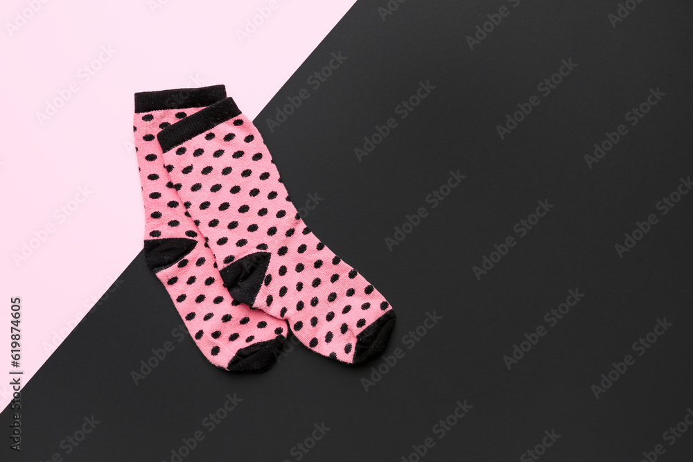 Pair of pink socks on color background