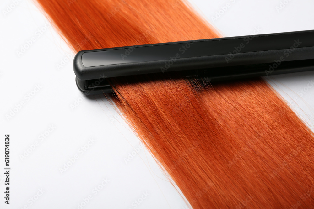 Ginger hair with straightening iron on white background, closeup