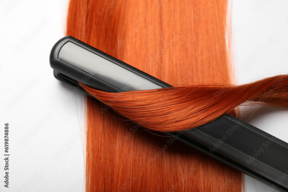 Ginger hair with straightening iron on white background, closeup