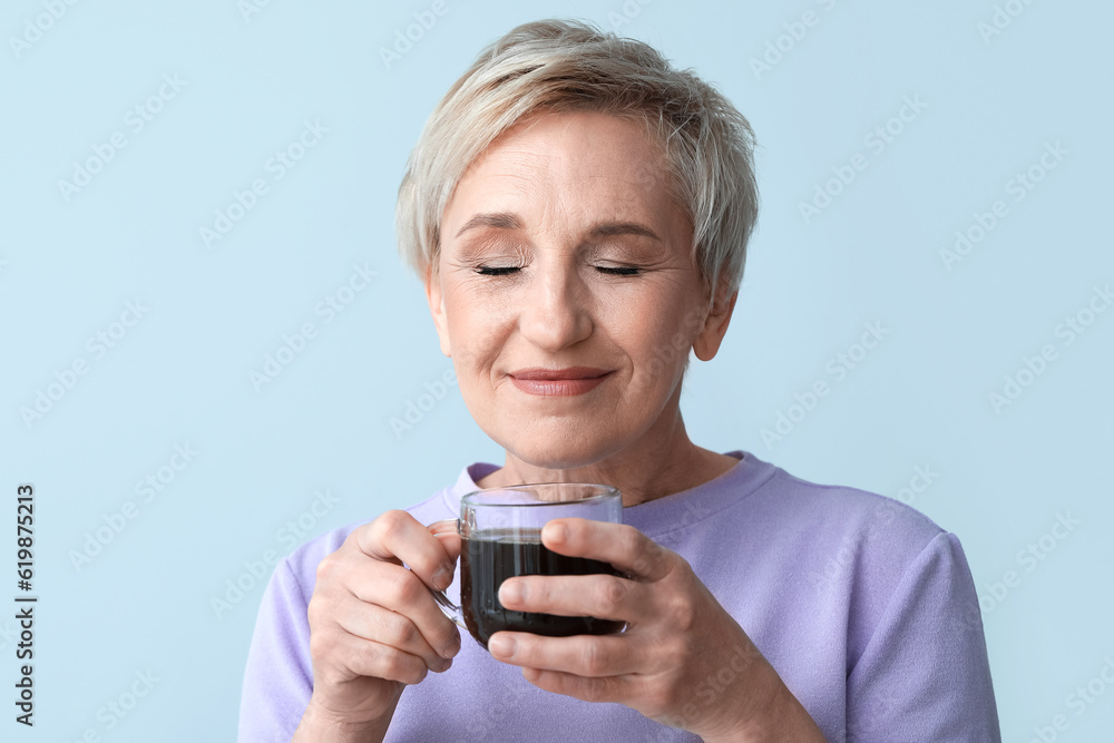 Mature woman with glass cup of coffee on light background, closeup