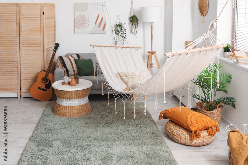 Interior of stylish living room with hammock, grey sofa and coffee table