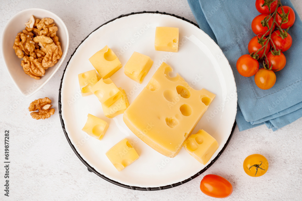 Stand and plate with pieces of Swiss cheese and tomatoes on white table