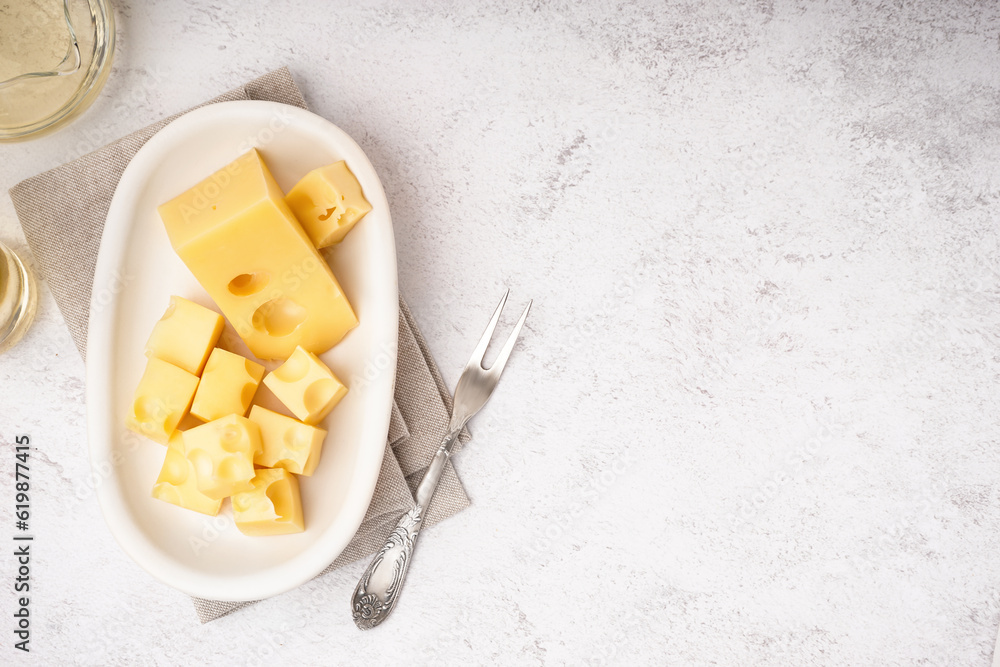 Plate with pieces of Swiss cheese on white table